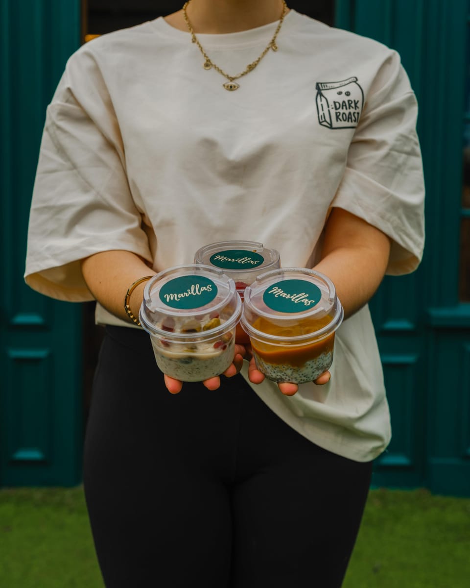 Three pots of overnight oats with Marillas lids, held out in both hands.